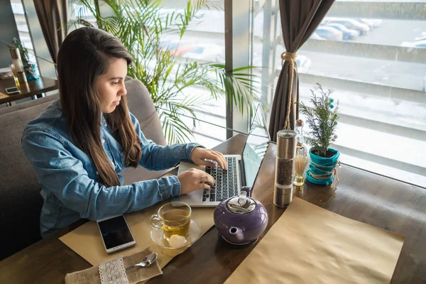 Женщина пьет чай в кафе и работает — стоковое фото