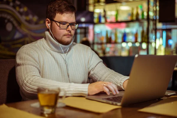 Handsome young man with laptop and cup in a cafe — Stock Photo, Image