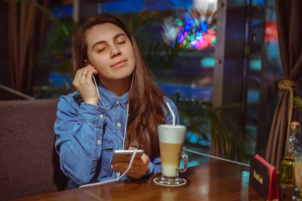 Music smartphone in female hand, on cafe interior background — Stock Photo, Image