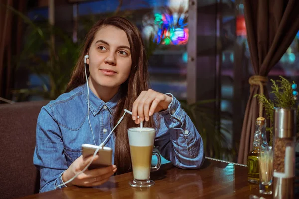 Music smartphone in female hand, on cafe interior background — Stock Photo, Image