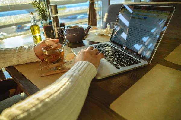 Man in sweater working on laptop in caffe on sunset — Stock Photo, Image