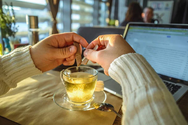 Человек в свитере работает на ноутбуке в кафе на закате — стоковое фото