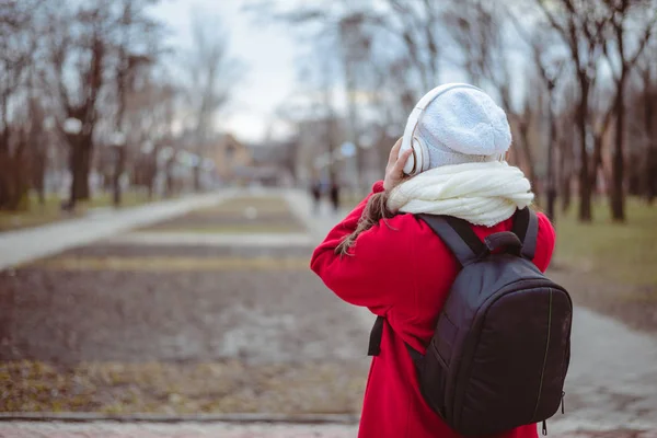 Portrait d'une fille heureuse écoutant de la musique en ligne avec des écouteurs sans fil à partir d'un smartphone en chapeau — Photo