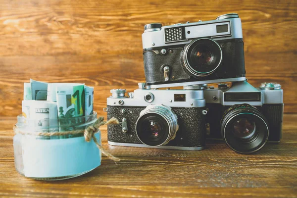 Jar with money and retro cameras — Stock Photo, Image