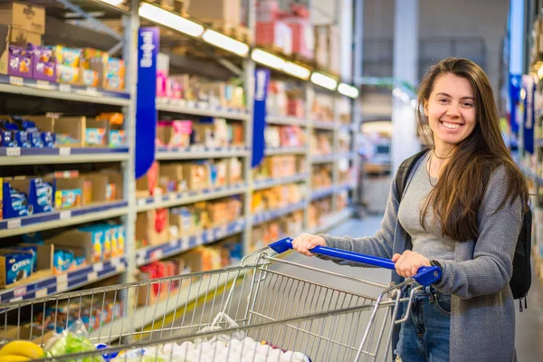 Glückliche junge Frau schiebt Einkaufswagen in Supermarkt — Stockfoto
