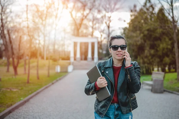 Young woman using a smart phone waling in the park — Stock Photo, Image
