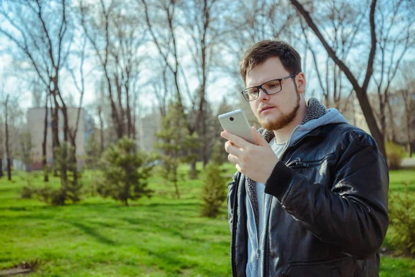 Yang homem com smartphone no parque — Fotografia de Stock