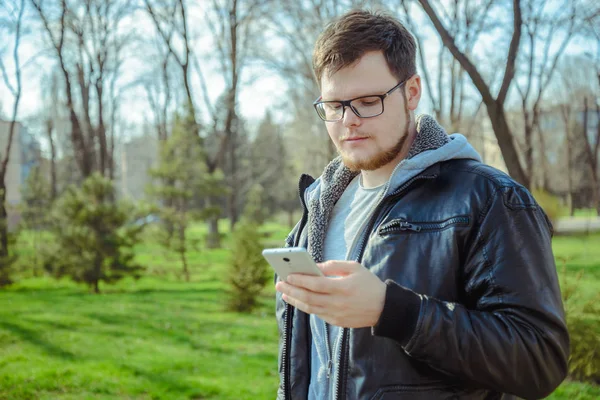 Yang homem com smartphone no parque — Fotografia de Stock