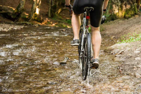 Mountain biker speeding through forest stream — Stock Photo, Image