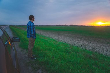 Araba gezisi adam sunrice karayolu üzerinde bakmak için durur