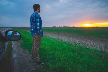 Araba gezisi adam sunrice karayolu üzerinde bakmak için durur