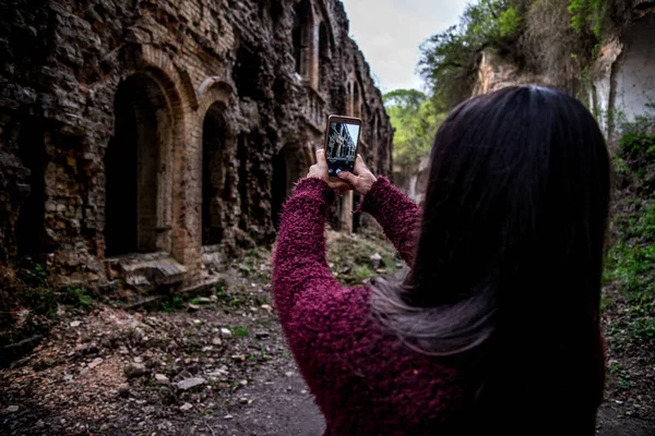 Young woman tourist photographing old ruins