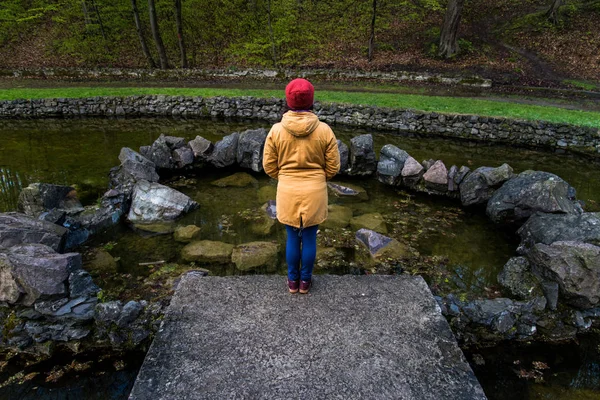 Жінка стоїть біля озера в міському парку і думає: — стокове фото