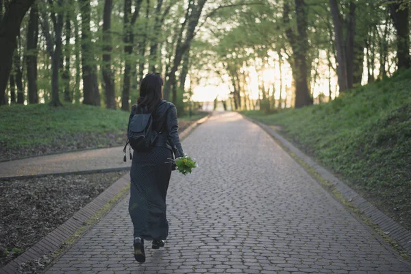 Mujer caminando por el parque con flores en las manos — Foto de Stock