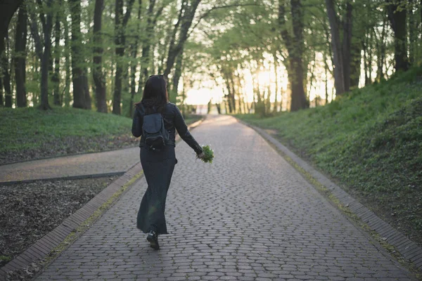 Donna passeggiando per il parco con fiori in mano — Foto Stock