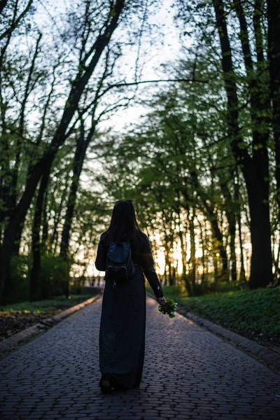 Femeie de mers pe jos prin parc cu flori în mâini — Fotografie, imagine de stoc