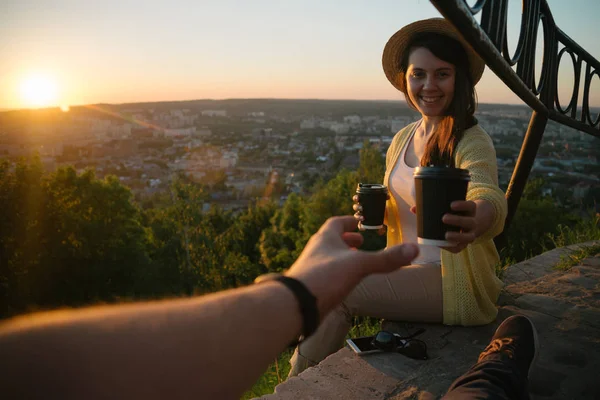 Žena dává kávě muž, zatímco oni sedí na kopci na východ slunce — Stock fotografie