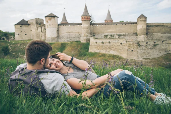 Lovely couple lies on ground in front of old castle — Stock Photo, Image