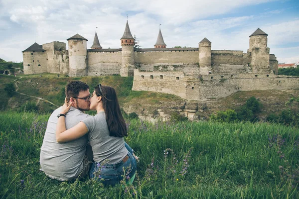 Lovely couple sits on ground in front of old castle — Stock Photo, Image