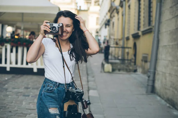 Mooie jongedame fotograaf lopen door oude stad straat met retro camera — Stockfoto