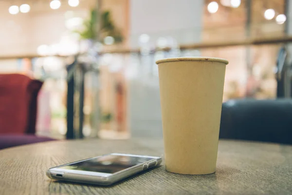 Coffee cup with mobile phone on the table — Stock Photo, Image