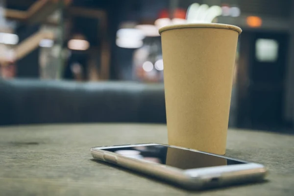 Coffee cup with mobile phone on the table — Stock Photo, Image