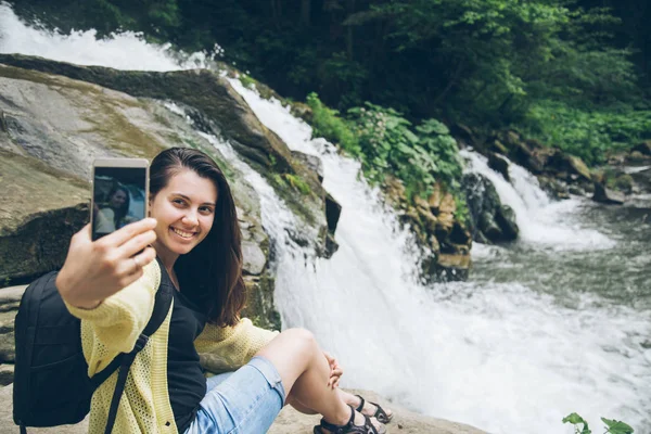 Mulher tirar foto no telefone de cachoeira no fundo — Fotografia de Stock