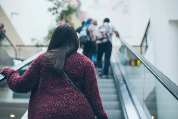 Young woman on escalator in mall — Stock Photo, Image