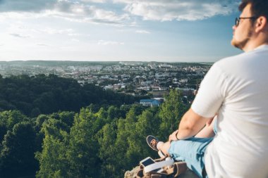 telefon ile tepe üzerinde oturan adam