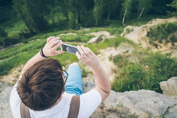 Man taking picture on his phone on the peak — Stock Photo, Image