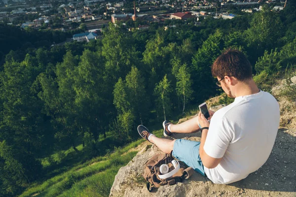 telefon ile tepe üzerinde oturan adam