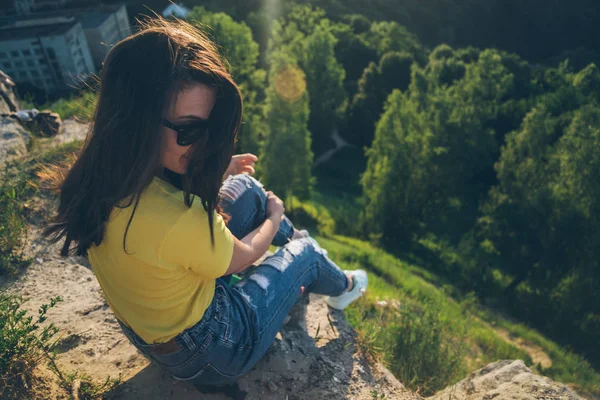 Junge hübsche Frau sitzt und lächelt auf dem Gipfel des Hügels — Stockfoto