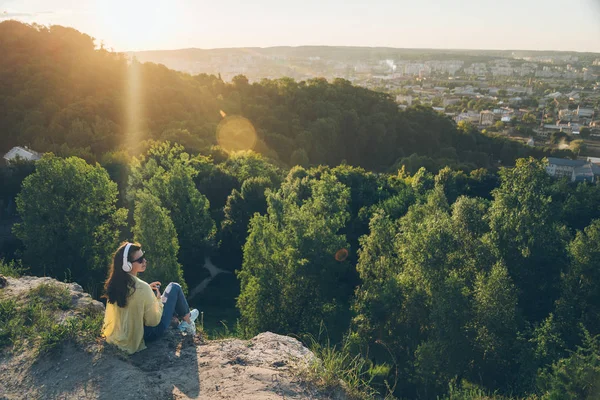 young pretty woman listing music on the top of the hill