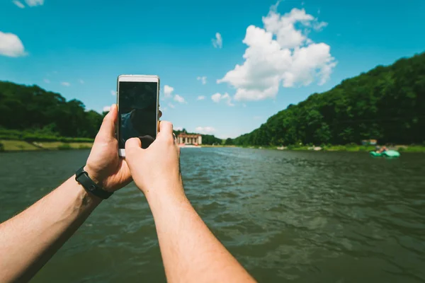Mãos dos homens segurar o telefone, tirando foto do lago — Fotografia de Stock
