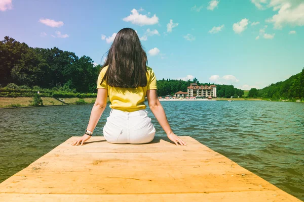 Donna seduta su un molo del lago — Foto Stock