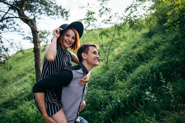 Namorado levar namorada em suas costas para cima na colina — Fotografia de Stock