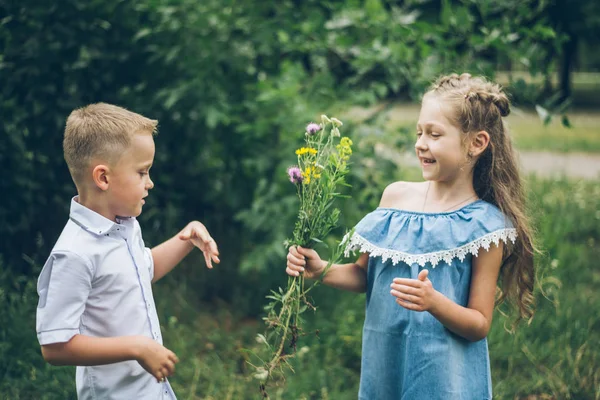 Маленький хлопчик дарує дівчинці купу квітів — стокове фото