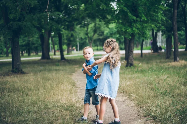Маленький хлопчик і дівчинка йдуть разом і тримають один одного за руки — стокове фото