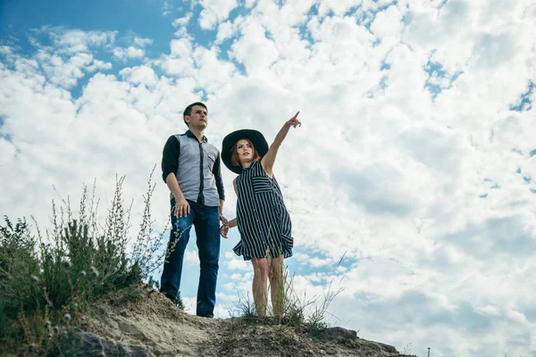 Young man with woman stands on the hill and points straight ahead — Stock Photo, Image