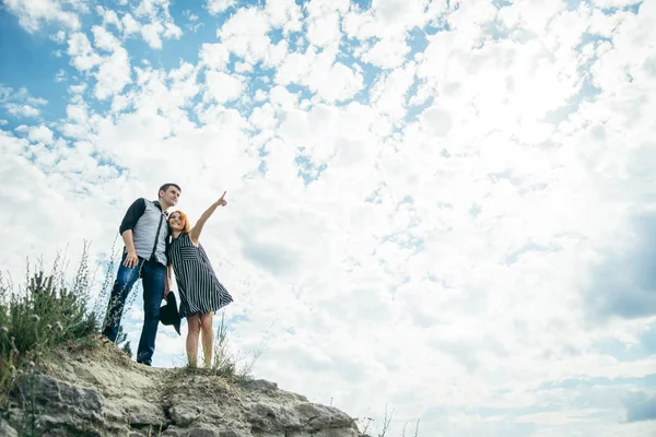 Young man with woman stands on the hill and points straight ahead — Stock Photo, Image