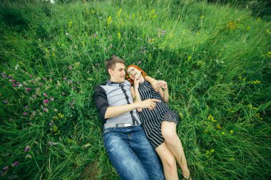 Genç mutlu güzel çift erkek ve kadın açık havada parlak güneşli günde yeşil çim üzerinde yalan