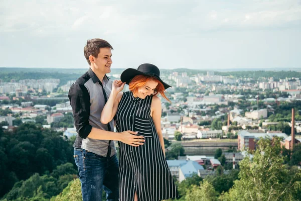 Cuplu în picioare pe deal îmbrățișare și în căutarea pe vedere la oraș — Fotografie, imagine de stoc