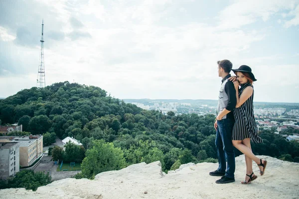 Пара, стоящая на холме обнимаясь и глядя на город — стоковое фото