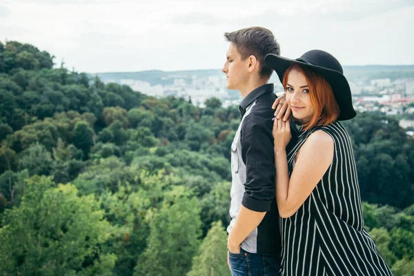 Casal de pé na colina abraçando e olhando para a vista da cidade — Fotografia de Stock