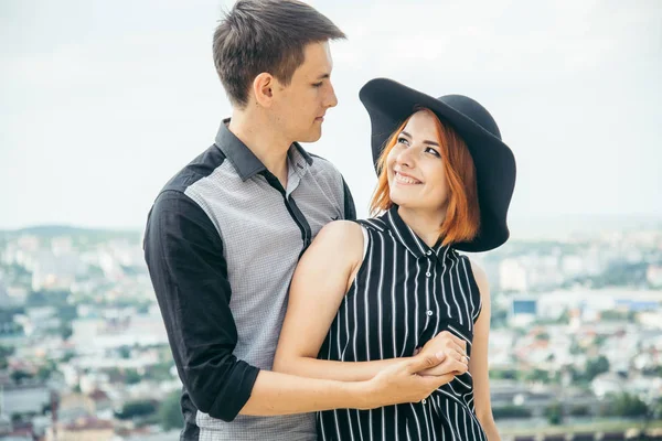 Pasangan berdiri di atas bukit memeluk dan melihat pemandangan kota — Stok Foto