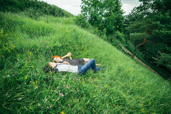 Giovane felice bella coppia uomo e donna sdraiati all'aperto nella luminosa giornata di sole sul prato verde — Foto Stock