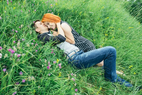 若い幸せな美しいカップル男と緑の芝生の明るい晴れた日に屋外に横たわる女 — ストック写真