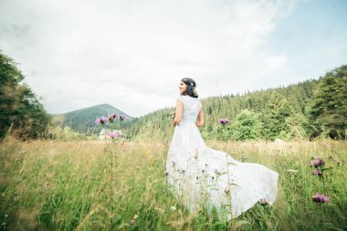 Bir sahada zarif beyaz elbise ayakta giyen güzel genç kadın