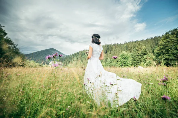 Bir sahada zarif beyaz elbise ayakta giyen güzel genç kadın
