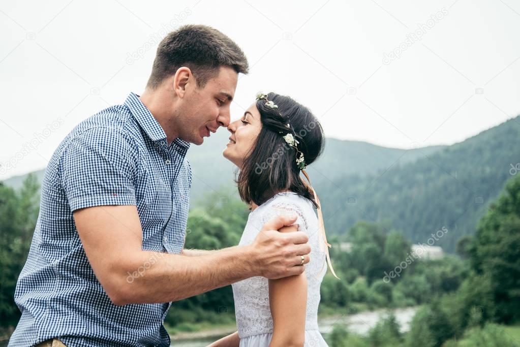 man with woman standing on the bridge across the river